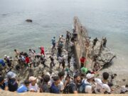 Marruecos culpa a fallo judicial español por crisis en Ceuta Decenas de personas agrupadas sobre rocas intentando rodear el espigón fronterizo con valla metálica hacia Ceuta.