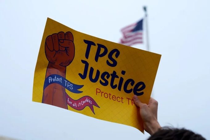 Deportados de EE. UU. llegan a Haití tras la cancelación del TPS Cartel de protesta por el fin del TPS para deportados de Haití frente a bandera de Estados Unidos.