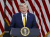 EE. UU. planea cobrar una nueva tarifa de 100.000 dólares para visas H-1B Donald Trump sonriendo en un podio presidencial ante banderas de EE. UU. respecto a las tarifas de visas H-1B.