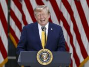 EE. UU. planea cobrar una nueva tarifa de 100.000 dólares para visas H-1B Donald Trump sonriendo en un podio presidencial ante banderas de EE. UU. respecto a las tarifas de visas H-1B.