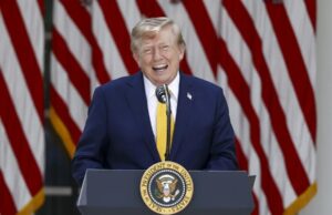 EE. UU. planea cobrar una nueva tarifa de 100.000 dólares para visas H-1B Donald Trump sonriendo en un podio presidencial ante banderas de EE. UU. respecto a las tarifas de visas H-1B.