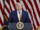 EE. UU. planea cobrar una nueva tarifa de 100.000 dólares para visas H-1B Donald Trump sonriendo en un podio presidencial ante banderas de EE. UU. respecto a las tarifas de visas H-1B.