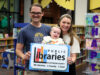 Homewood Public Library lanza iniciativas por tarjeta de biblioteca Familia con un bebé sostiene un cartel de las bibliotecas del condado de Jefferson en Alabama.