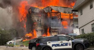 Incendio en apartamentos de Birmingham deja 20 desplazados Voraz incendio consume edificio de apartamentos en Birmingham con patrulla policial en primer plano.