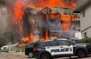 Incendio en apartamentos de Birmingham deja 20 desplazados Voraz incendio consume edificio de apartamentos en Birmingham con patrulla policial en primer plano.