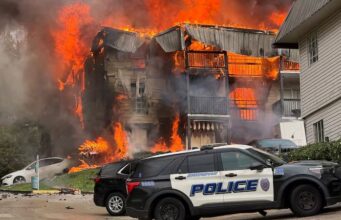 Incendio en apartamentos de Birmingham deja 20 desplazados Voraz incendio consume edificio de apartamentos en Birmingham con patrulla policial en primer plano.