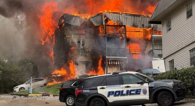 Incendio en apartamentos de Birmingham deja 20 desplazados Voraz incendio consume edificio de apartamentos en Birmingham con patrulla policial en primer plano.