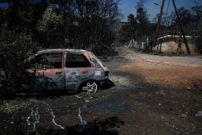 Incendio en Grecia fuera de control devora 12.600 hectáreas Coche calcinado junto a árboles quemados tras un grave incendio en Grecia.