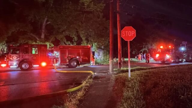 Camiones de bomberos de Huntsville con luces de emergencia atendiendo un incendio nocturno en Meadow Drive.