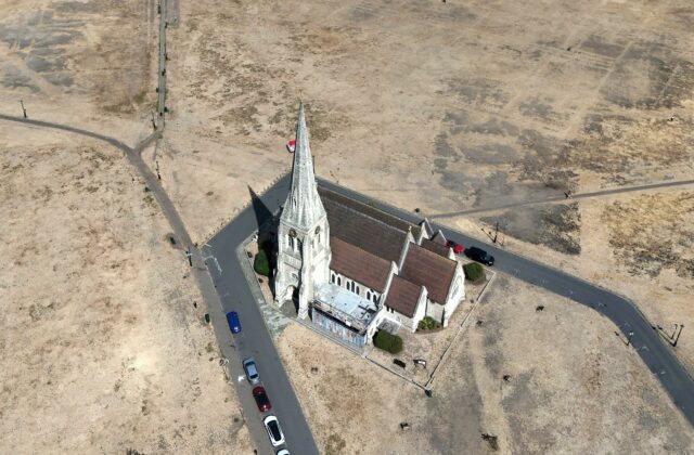Vista aérea de terreno seco por ola de calor alrededor de una iglesia en Inglaterra.