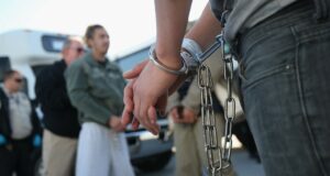 Inmigración en EE. UU. intensifica arrestos con el plan 287g Detenido bajo custodia con esposas y cadenas metálicas durante un operativo de inmigración de las autoridades.
