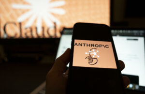 Inteligencia artificial muestra conductas autónomas y engañosas Mano sosteniendo un teléfono con el logo de Anthropic frente a una pantalla con el nombre de Claude.