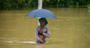 Monzón en India deja 115 muertos y miles de evacuados Hombre caminando con el agua a la cintura sosteniendo una sombrilla durante las inundaciones por el monzón en India.