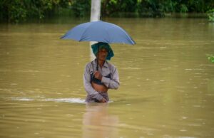 Monzón en India deja 115 muertos y miles de evacuados Hombre caminando con el agua a la cintura sosteniendo una sombrilla durante las inundaciones por el monzón en India.