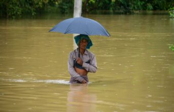 Monzón en India deja 115 muertos y miles de evacuados Hombre caminando con el agua a la cintura sosteniendo una sombrilla durante las inundaciones por el monzón en India.
