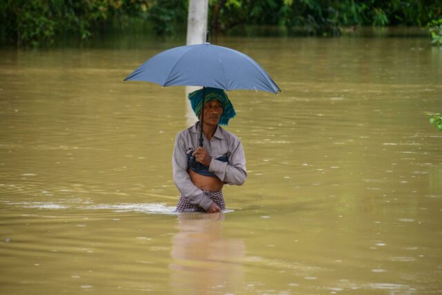 Las lluvias e inundaciones en la India causan al menos 115 muertos en los últimos días Hombre caminando con el agua a la cintura sosteniendo una sombrilla durante las inundaciones por el monzón en India.