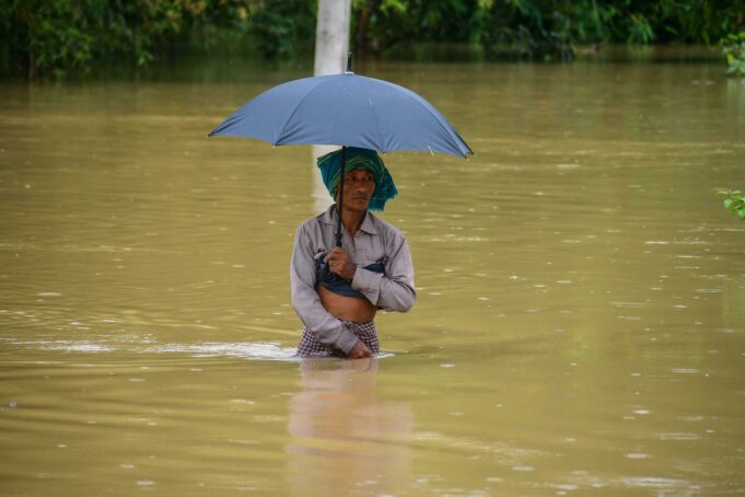 Monzón en India deja 115 muertos y miles de evacuados Hombre caminando con el agua a la cintura sosteniendo una sombrilla durante las inundaciones por el monzón en India.