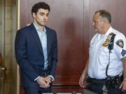 Luigi Mangione se declara culpable por crimen de Brian Thompson Luigi Mangione en traje formal y esposado junto a un oficial dentro de un tribunal de Nueva York.