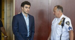 Luigi Mangione se declara culpable por crimen de Brian Thompson Luigi Mangione en traje formal y esposado junto a un oficial dentro de un tribunal de Nueva York.