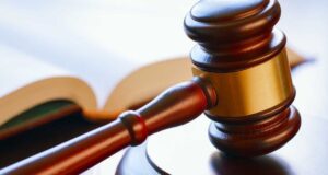 Condenan a banda por tráfico de metanfetamina en Alabama Mazo de madera de juez reposando sobre una mesa junto a un libro de leyes en un tribunal.