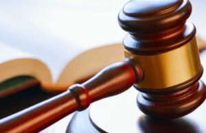 Condenan a banda por tráfico de metanfetamina en Alabama Mazo de madera de juez reposando sobre una mesa junto a un libro de leyes en un tribunal.