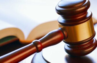 Condenan a banda por tráfico de metanfetamina en Alabama Mazo de madera de juez reposando sobre una mesa junto a un libro de leyes en un tribunal.
