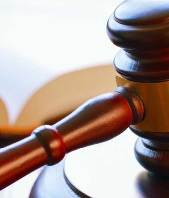 Condenan a banda por tráfico de metanfetamina en Alabama Mazo de madera de juez reposando sobre una mesa junto a un libro de leyes en un tribunal.