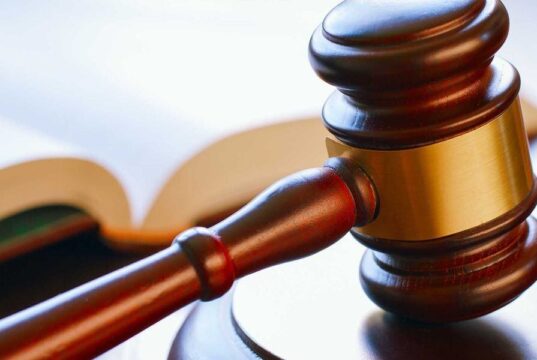 Condenan a banda por tráfico de metanfetamina en Alabama Mazo de madera de juez reposando sobre una mesa junto a un libro de leyes en un tribunal.