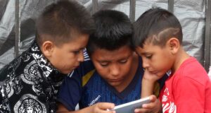 Prohibición de celulares en escuelas de México abre debate Tres niños observan la pantalla de un celular en México durante la regulación de dispositivos escolares.