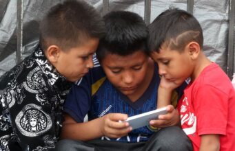 Prohibición de celulares en escuelas de México abre debate Tres niños observan la pantalla de un celular en México durante la regulación de dispositivos escolares.