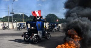 Subsidio a combustibles en Perú aliviará a transportistas Mototaxis con banderas de Perú protestan en una calle bloqueada con neumáticos en llamas.