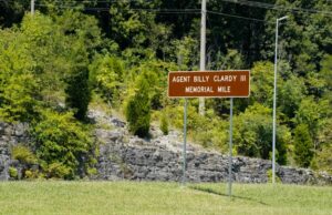 Dedican tramo de la U.S. 72 al agente Billy Clardy III Señal de tránsito marrón con la inscripción Agent Billy Clardy III Memorial Mile a la orilla de la carretera.