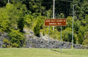 Dedican tramo de la U.S. 72 al agente Billy Clardy III Señal de tránsito marrón con la inscripción Agent Billy Clardy III Memorial Mile a la orilla de la carretera.