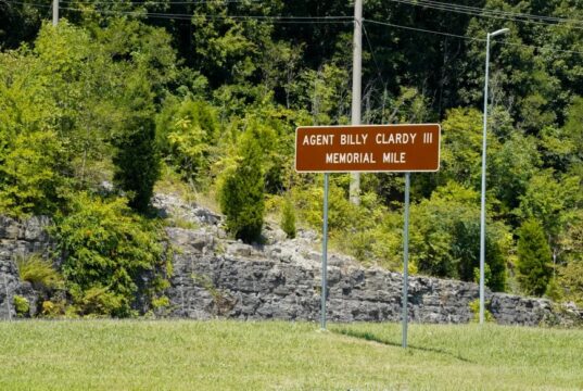 Dedican tramo de la U.S. 72 al agente Billy Clardy III Señal de tránsito marrón con la inscripción Agent Billy Clardy III Memorial Mile a la orilla de la carretera.