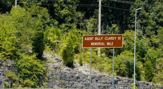 Dedican tramo de la U.S. 72 al agente Billy Clardy III Señal de tránsito marrón con la inscripción Agent Billy Clardy III Memorial Mile a la orilla de la carretera.