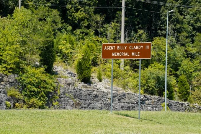 Dedican tramo de la U.S. 72 al agente Billy Clardy III Señal de tránsito marrón con la inscripción Agent Billy Clardy III Memorial Mile a la orilla de la carretera.