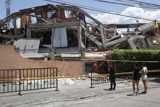 Personas observando la estructura colapsada de un edificio destruido por el terremoto en Colombia.