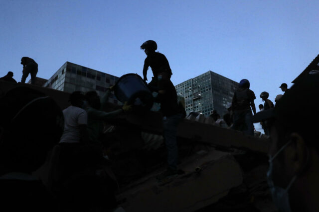 Rescatistas y voluntarios remueven escombros tras el terremoto en Colombia durante el atardecer.