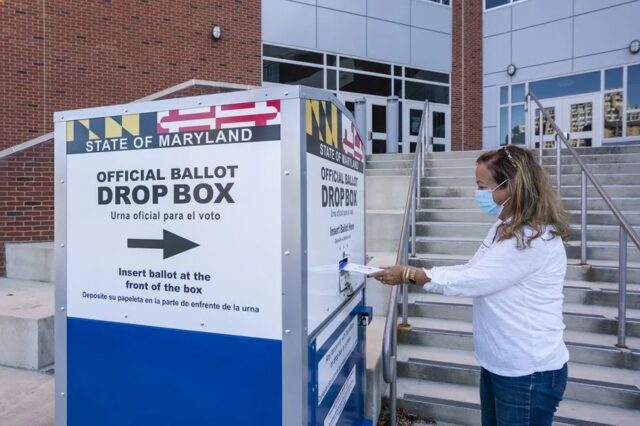 Mujer depositando su papeleta en una urna oficial para voto por correo en Estados Unidos.