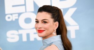 Anne Hathaway sufre ataques conservadores en redes sociales Retrato de la actriz Anne Hathaway en una alfombra roja luciendo peinado de cola de caballo y labial rojo.