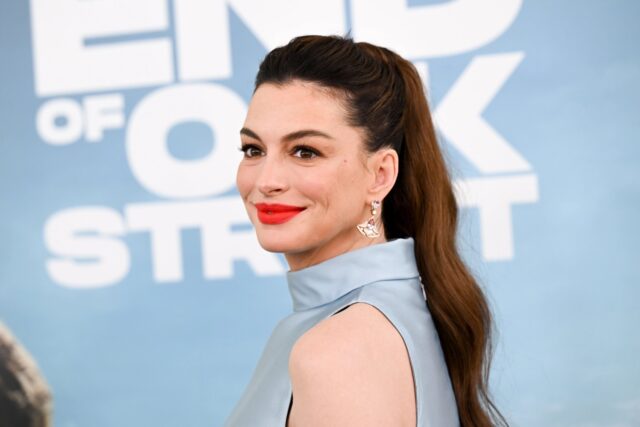Retrato de la actriz Anne Hathaway en una alfombra roja luciendo peinado de cola de caballo y labial rojo.