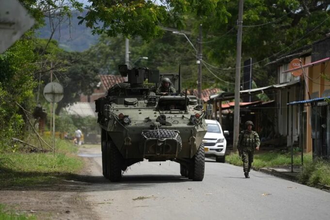 Órdenes de captura contra 46 exnegociadores en Colombia Vehículo blindado militar y soldado patrullando una calle rural en Colombia tras reactivación de capturas.