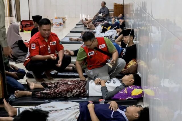 Socorristas atienden a estudiantes en suelo de hospital tras masiva intoxicación alimentaria en Indonesia.