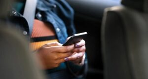 Motion Assist de Google combate el mareo al usar el móvil Pasajera con cinturón de seguridad usando un smartphone en un coche para probar Motion Assist contra el mareo.