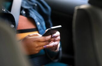 Motion Assist de Google combate el mareo al usar el móvil Pasajera con cinturón de seguridad usando un smartphone en un coche para probar Motion Assist contra el mareo.